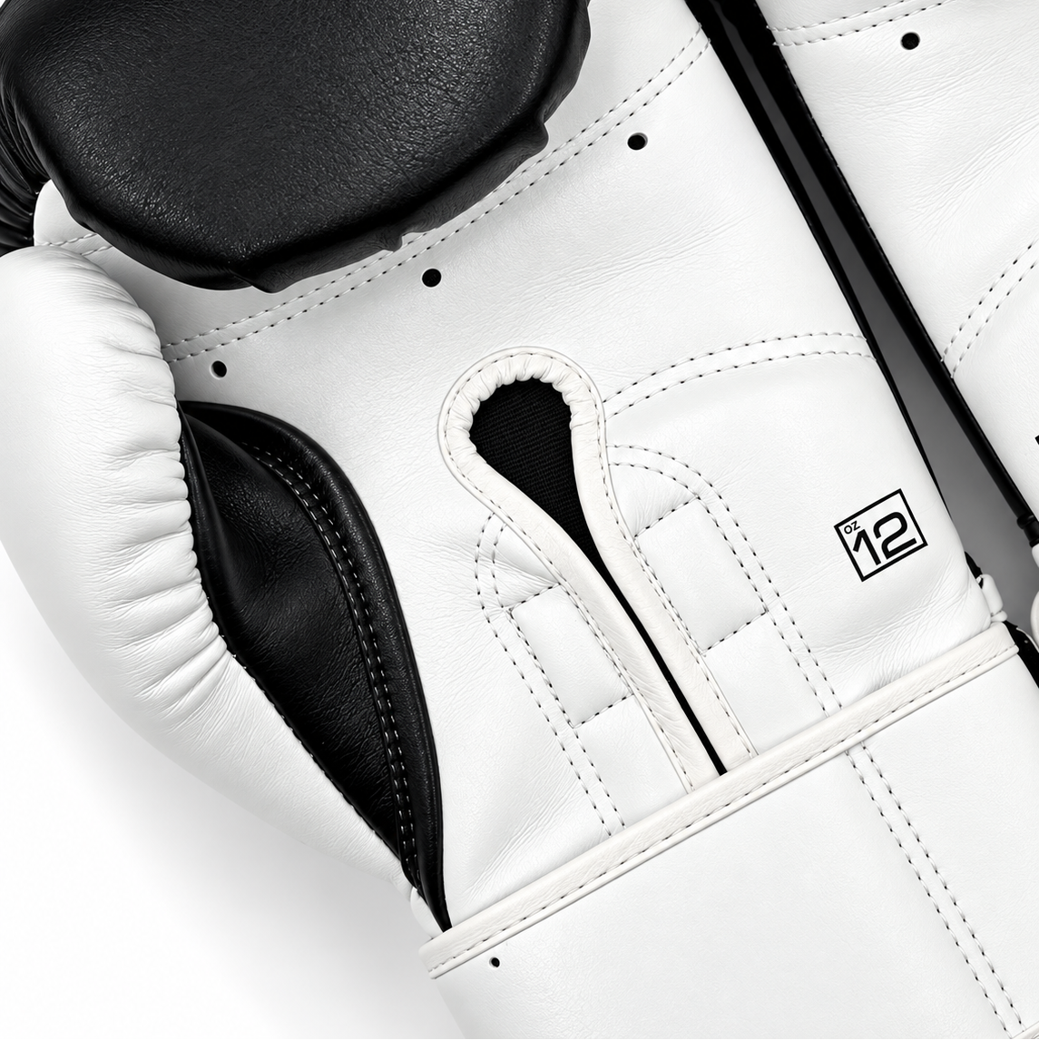 Close-up of a pair of boxing gloves in white and black leather, showing the padded knuckle area, stitching, and a small square logo on the white glove.