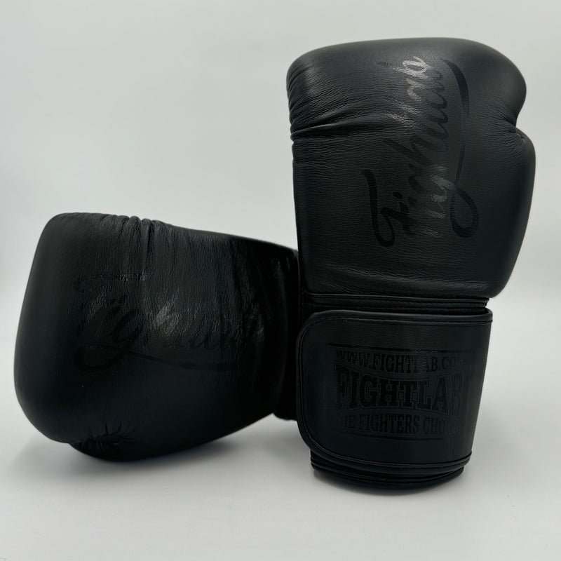A pair of black leather boxing gloves with embossed branding, displayed on a light gray background.