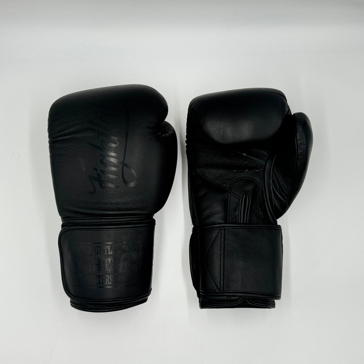 A pair of black leather boxing gloves displayed side-by-side on a light gray background.